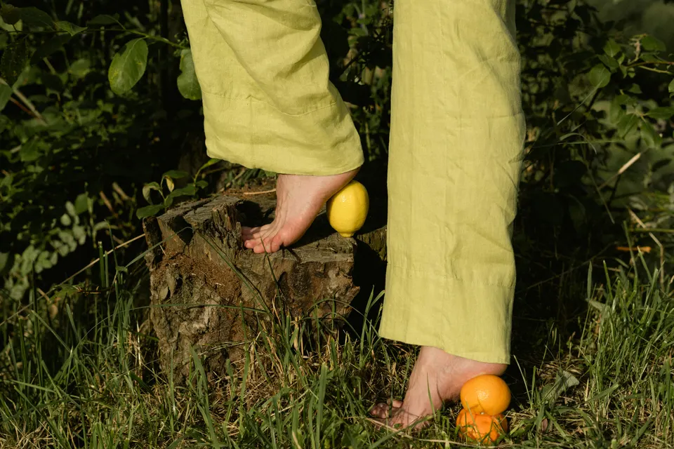 Bare feet in grass framed with lemons and oranges.