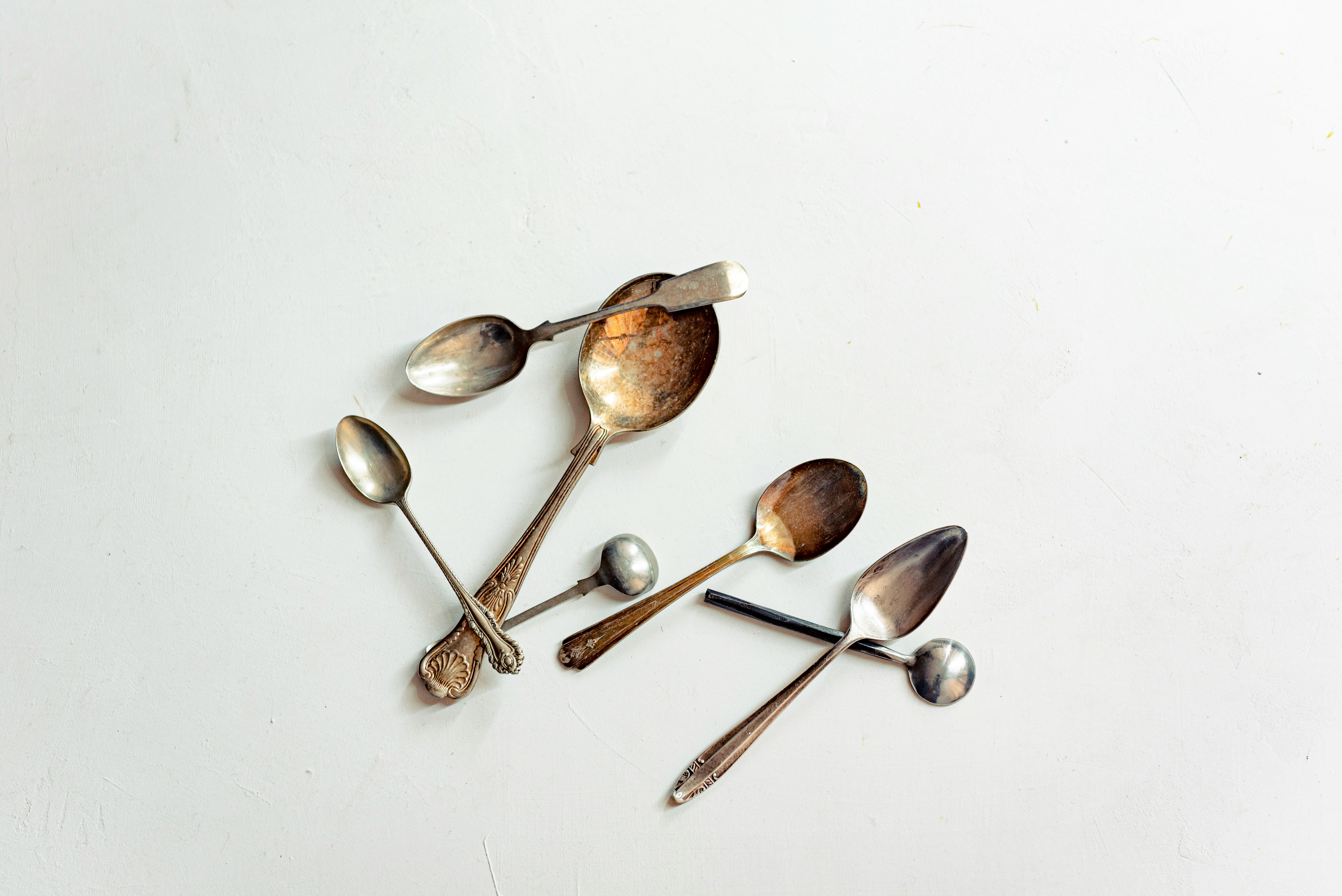 A collection of vintage spoons on a white surface